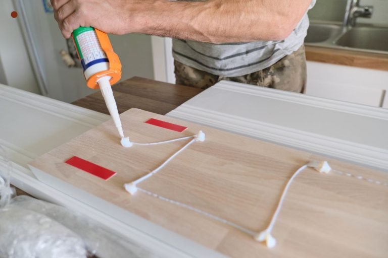 A man uses a glue gun to attach wood pieces to a counter, demonstrating furniture repair techniques.